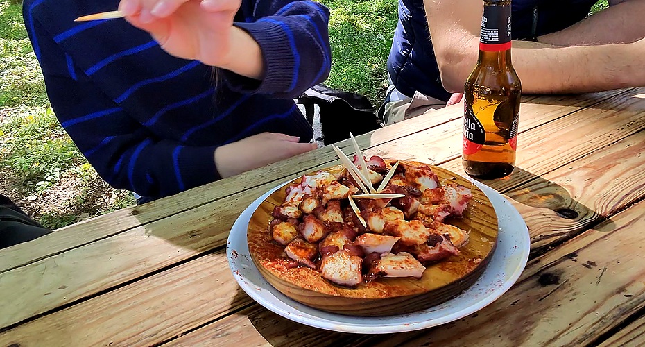 Pulpo á feira recién aliñado en plato de madera con aceite de oliva y pimentón en la feria de Castroverde