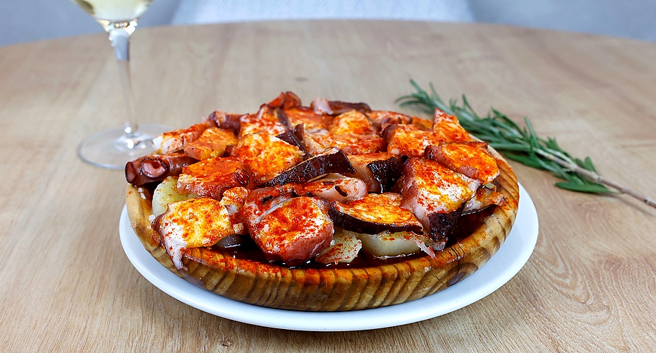 Pulpo á feira típico de Galicia servido en plato de madera con pimentón y aceite